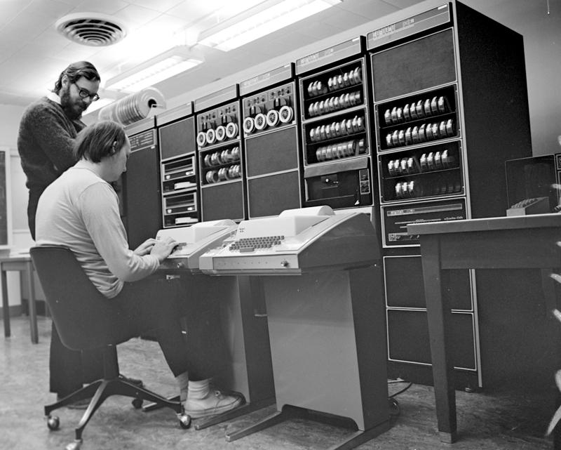 Ritchie and Ken sitting in front of a PDP-11 computer. Photo credit: dmr (http://cm.bell-labs.com/cm/cs/who/dmr/picture.html)