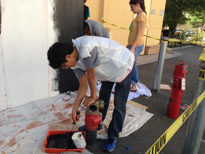 Daniel Arden applies chalkboard paint to the unfinished Before I Die wall. Photo Courtesy of Meredith Bransfield