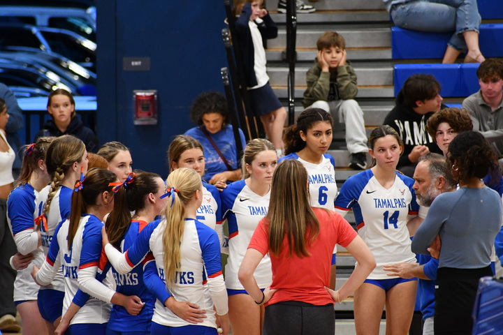 The Tam girls volleyball team huddles with their coaches.